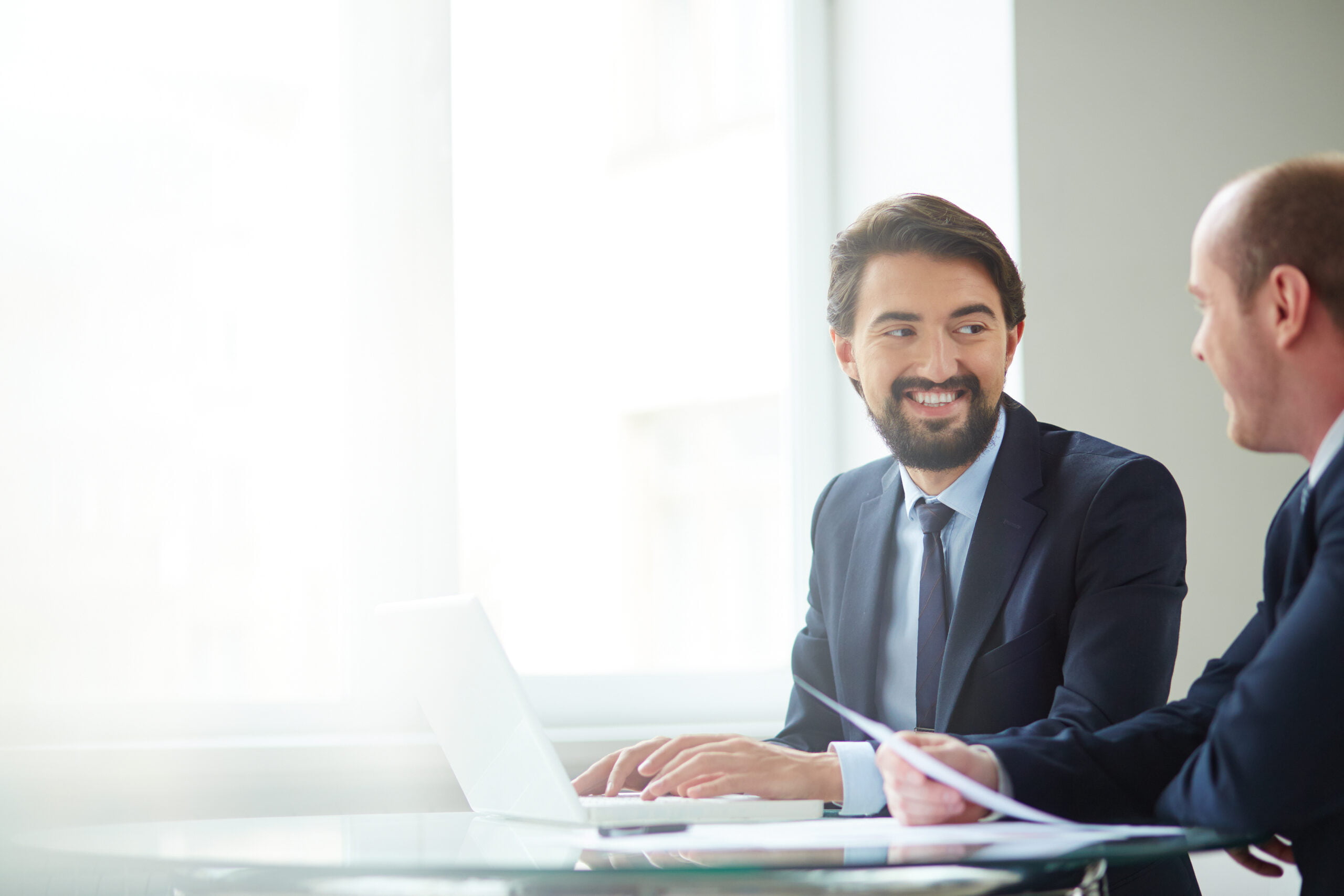 Image of handsome businessman typing and communicating with to his colleague at meeting